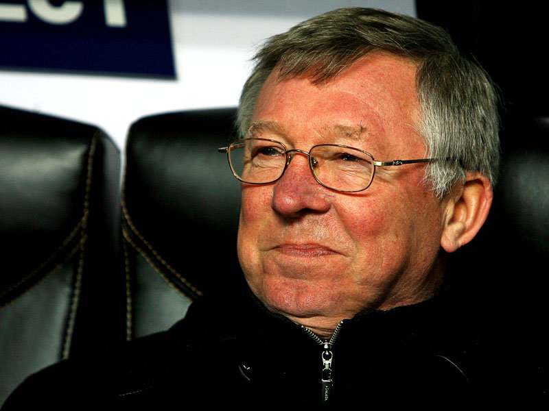 Sir Alex Ferguson smiling on the bench during a game in the Champions League.